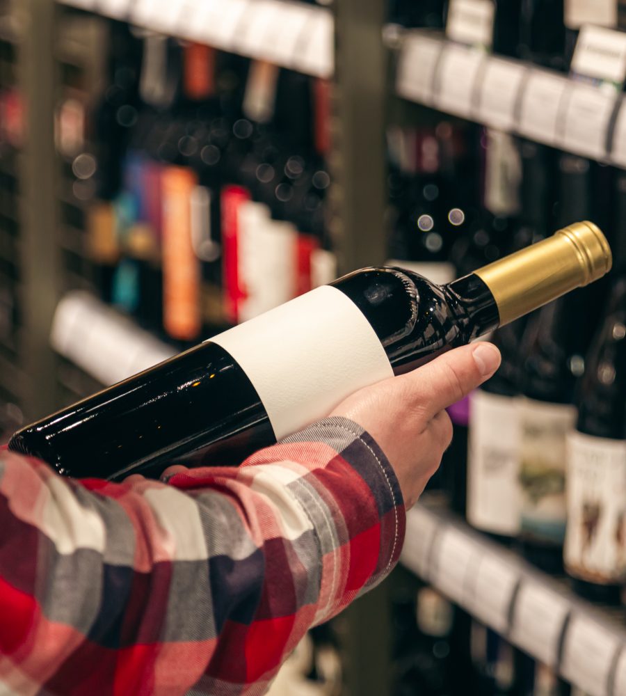 male customer holding bottle red wine close up